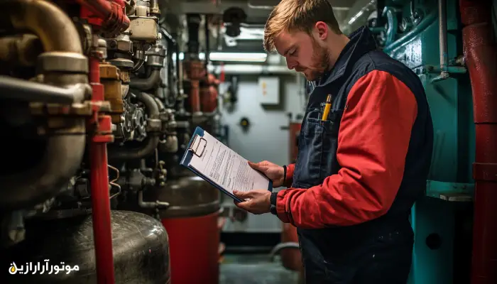 مهندس فنی دریایی در حال بررسی چک‌لیست تعمیر و نگهداری موتور کشتی با استفاده از تخته شاسی در اتاق موتورخانه – نمایی از پایش دوره‌ای وضعیت روغن موتور