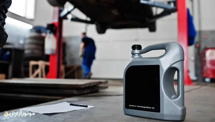 ظرف روغن موتور خاکستری در کنار جک خودرو در تعمیرگاه