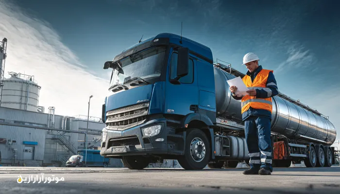 راننده کامیون موتورازین در حال بررسی مدارک توزیع روغن موتور و صنعتی کنار تانکر حمل، نماد دقت و مسئولیت‌پذیری در شبکه پخش