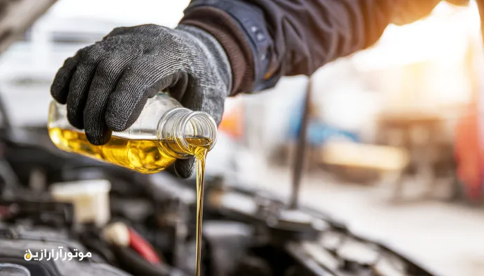 کلوزآپ تعویض روغن خودرو پیمانکاری در کارگاه دشتی با پس‌زمینه خطوط گاز و ابزار صنعتی. روغن موتور دشتی