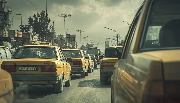 صف طولانی تاکسی‌های زرد در خیابان شلوغ شهری با نور غروب و آسمان نیمه‌ابری