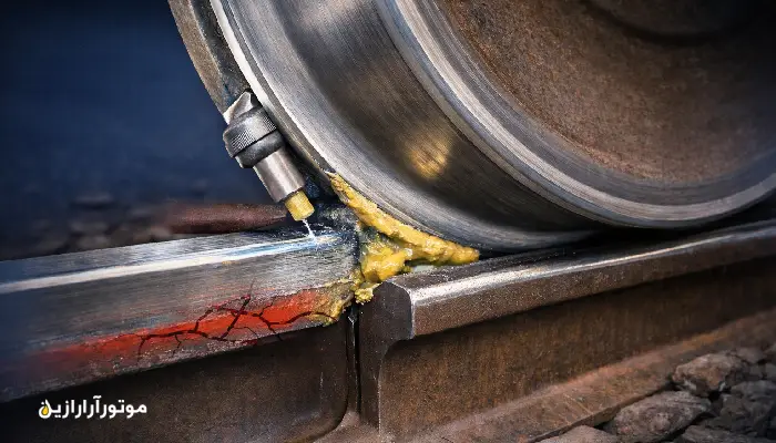 روانکاری تماس چرخ و ریل با گریس فلنج؛ نمای نزدیک از نازل تزریق گریس روی گوشه گیج ریل برای کاهش سایش فلنج و صدای قوس